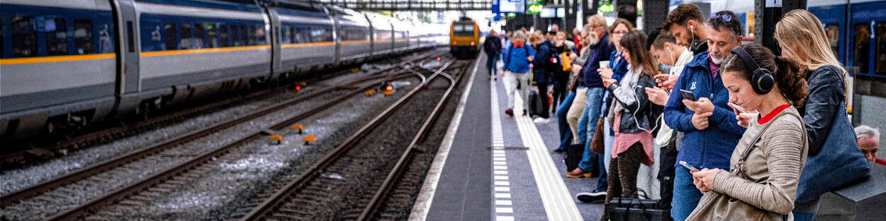 Treinstation met een vol perron met wachtende mensen